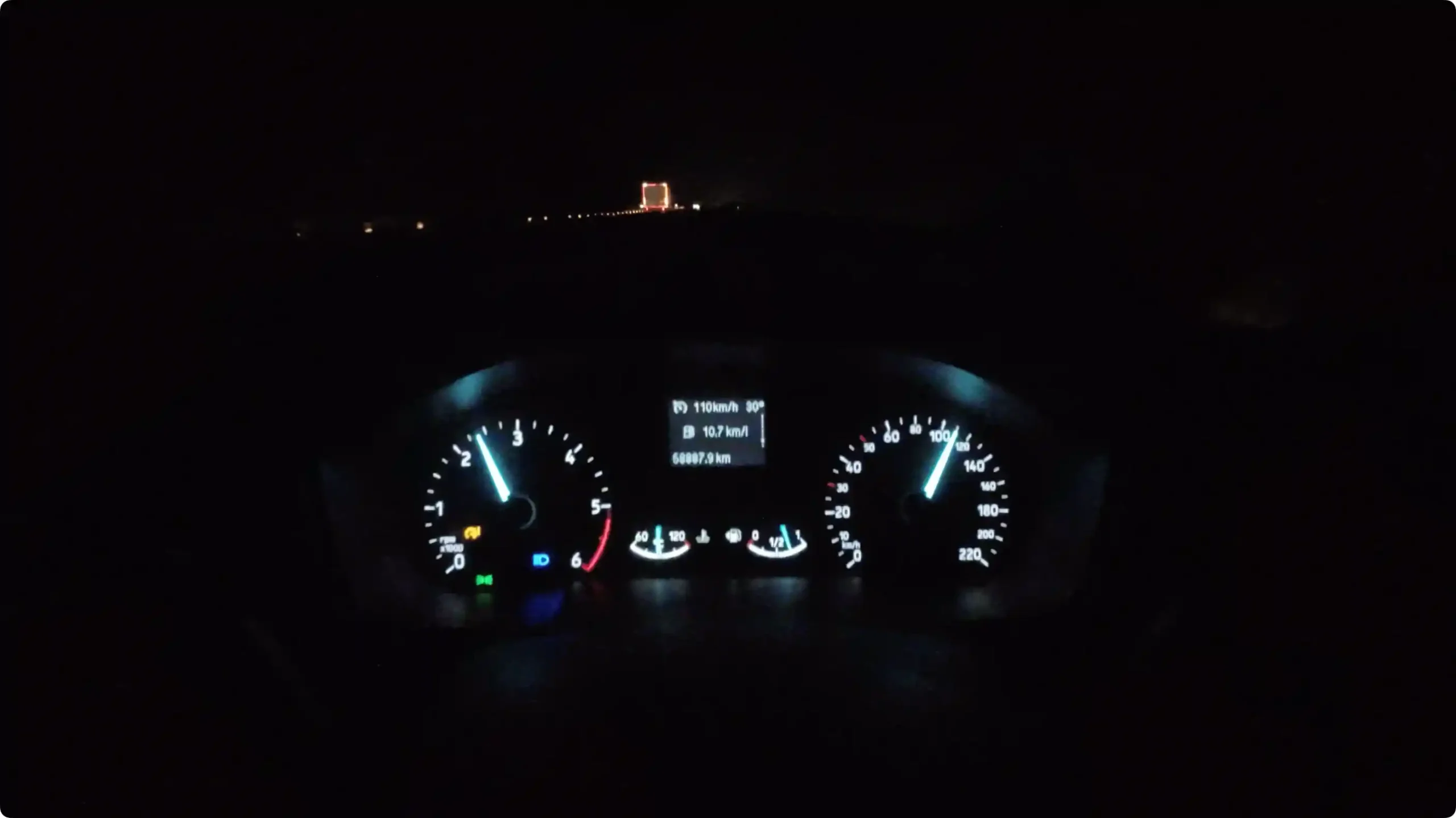 A glowing car dashboard speedometer showing 110 kmph during a night drive on the empty Agra-Lucknow Expressway