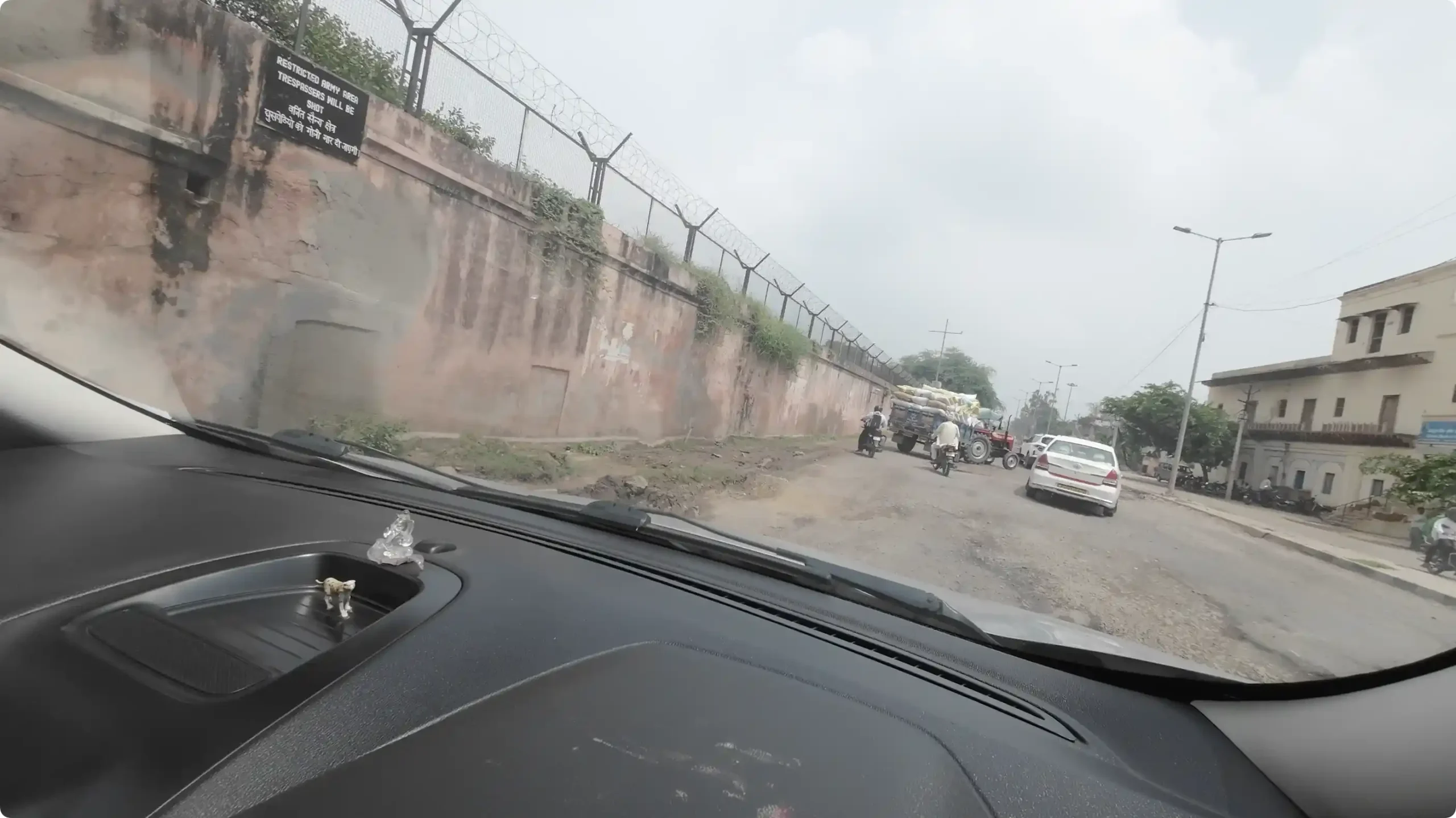 A narrow, broken dirt road filled with muddy potholes and heavy tractor traffic in Bharatpur on the way to Mathura