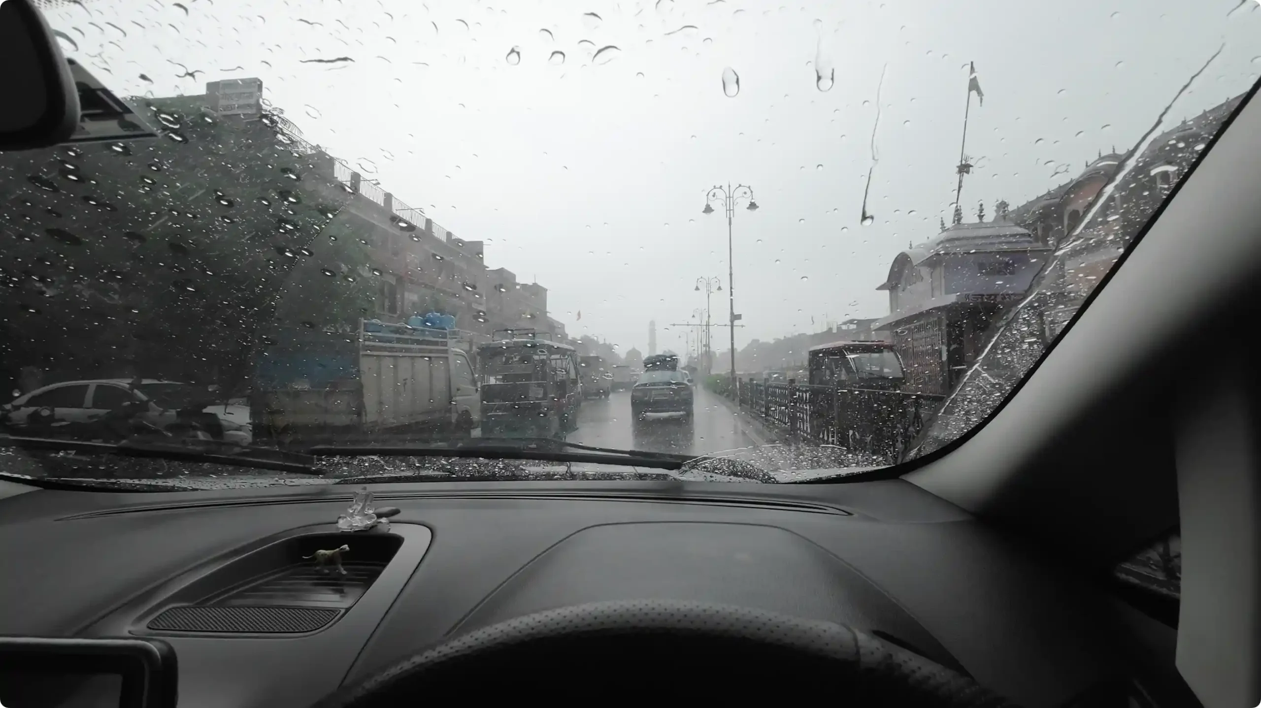 Dashboard view from inside a car driving through heavy monsoon rain on the wet streets of Jaipur