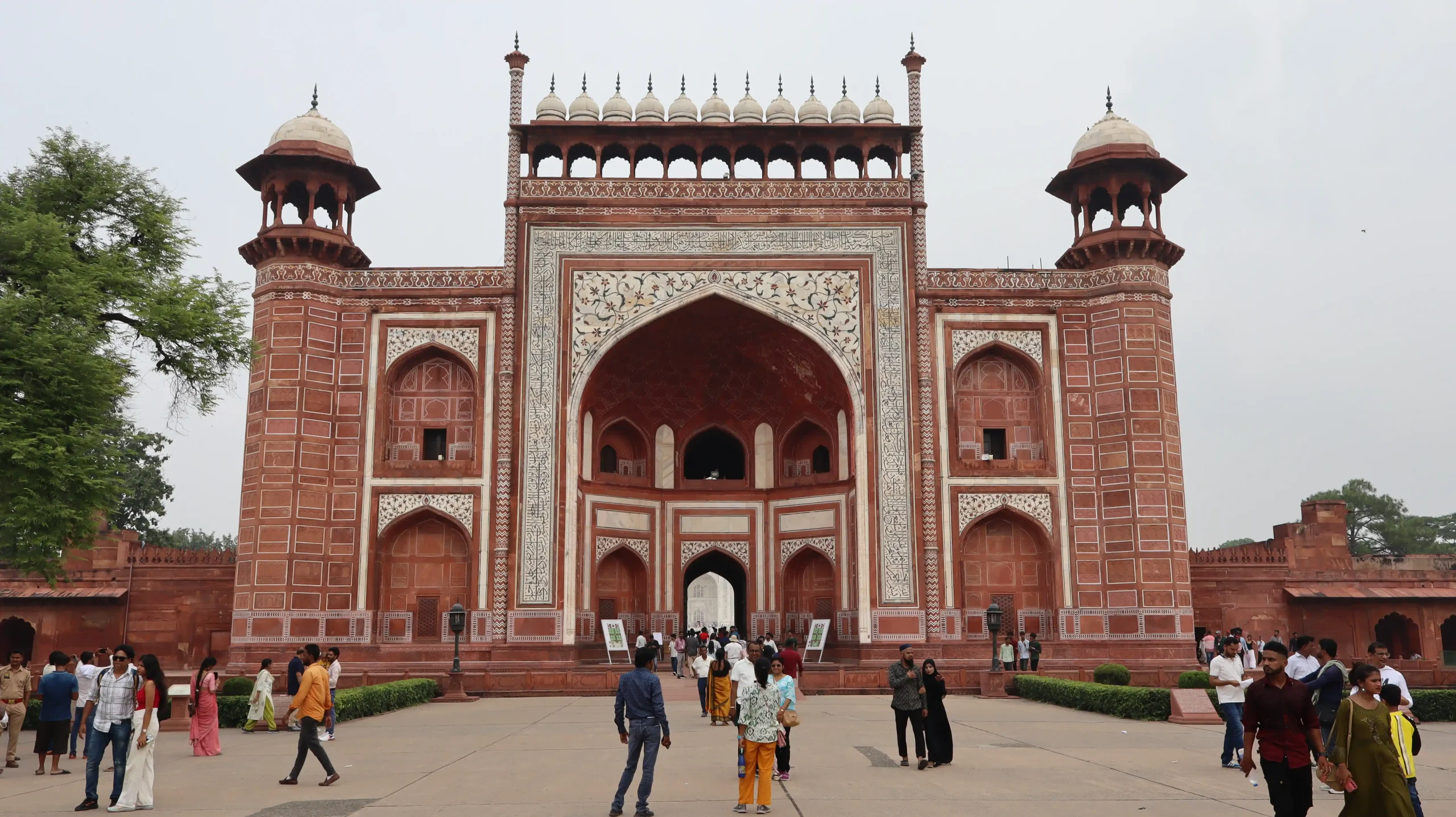 A beautiful low-angle shot looking through a dark red sandstone archway framing the brilliant white marble Taj Mahal in the morning